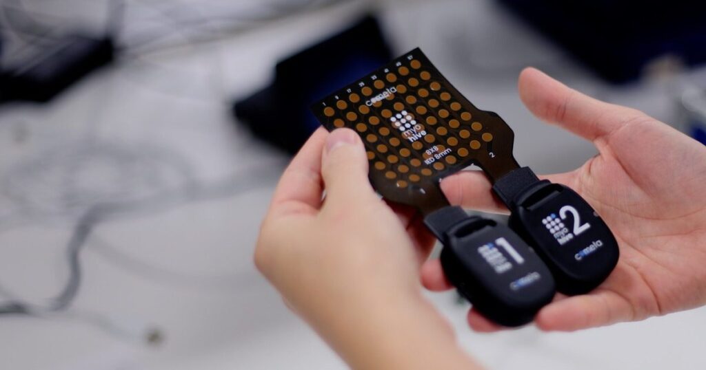 Cometa Myohive Sender mit angeschlossenem 8x8-Elektroden-Array in den Händen.